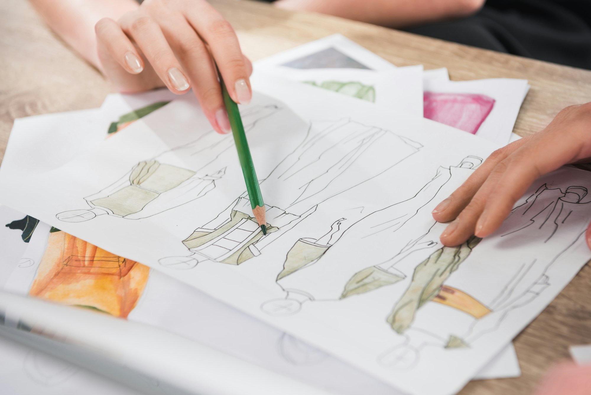 cropped shot of fashion designers working with blueprints of models